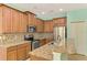 Well-lit kitchen with granite counters and backsplash, stainless steel appliances, and brown cabinetry at 9022 Coachman Dr, Venice, FL 34293