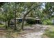 Exterior shot of the home with a gravel driveway and covered in mature, shady landscaping at 9625 Erie Rd, Parrish, FL 34219