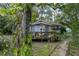 Exterior shot of the home with a covered porch surrounded by mature, shady landscaping at 9625 Erie Rd, Parrish, FL 34219