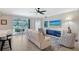 Spacious living room featuring a white leather sofa, ceiling fan, and serene views of the screened lanai and lush landscape at 1017 Tidewater Shores Loop # 1017, Bradenton, FL 34208