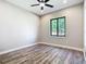Bright bedroom with wood-look flooring and ceiling fan, window overlooking lush greenery at 10588 Kidron Ave, Englewood, FL 34224