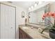 Bright bathroom featuring granite countertops, a large mirror, vanity lighting, and a decorative orchid at 1170 Bird Bay Way # 206, Venice, FL 34285