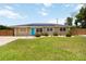 Attractive one-story home featuring a manicured lawn, blue door, solar panels, and privacy fence at 1212 Princeton Ave, Bradenton, FL 34207