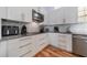 Bright kitchen with wooden floors, white cabinets, modern appliances, and gray countertops at 12214 Hernando Rd, North Port, FL 34287