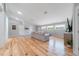 Spacious living room with light hardwood floors, a comfortable gray sectional sofa, and large windows, ideal for relaxation at 12214 Hernando Rd, North Port, FL 34287
