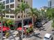 A charming street view with palm trees, outdoor cafes with vibrant red umbrellas, and unique storefronts at 1350 Main St # 1703, Sarasota, FL 34236