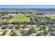 Expansive aerial view of a residential community with lush greenery, a pond, and nearby commercial establishments at 15208 21St E Ave, Bradenton, FL 34212