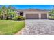 Well-maintained tan home with a three-car garage, paver driveway, and lush landscaping at 15208 21St E Ave, Bradenton, FL 34212