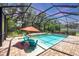A screened-in outdoor pool area with comfortable seating, an orange umbrella, and well-maintained brick pavers at 15208 21St E Ave, Bradenton, FL 34212