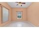 An empty bedroom with a ceiling fan and tiled floor is flooded with natural light from the window at 1651 Red Oak Ln, Port Charlotte, FL 33948