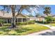 View of a charming home with a screened porch, mature tree, and meticulously maintained lawn at 1651 Red Oak Ln, Port Charlotte, FL 33948