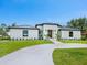 Modern home with a circular driveway, lush lawn, and dark metal roof at 180 Lookout Point Dr, Osprey, FL 34229