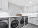 Modern laundry room with stylish white cabinets, marbled accent wall, and stainless steel appliances at 180 Lookout Point Dr, Osprey, FL 34229