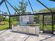 Outdoor kitchen in screened lanai with stainless steel grill and mini fridges at 180 Lookout Point Dr, Osprey, FL 34229