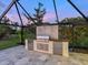 Outdoor kitchen in screened lanai with stainless steel grill and mini fridges at twilight at 180 Lookout Point Dr, Osprey, FL 34229