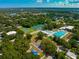 Gorgeous aerial view of multiple tennis courts and pool, nestled within a tree-lined community with clear blue skies at 2110 Craft Ln, Sarasota, FL 34239