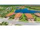 An aerial view of a townhome community with red-tiled roofs, a serene lake, and lush landscaping at 24065 Canterwood Way, Venice, FL 34293