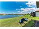 Waterfront backyard with lawn, landscaping and two blue Adirondack chairs by the lake at 24065 Canterwood Way, Venice, FL 34293