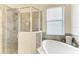 Corner glass enclosed shower and tub featuring stylish tile work and a small window at 24065 Canterwood Way, Venice, FL 34293