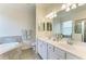 Bathroom featuring a double vanity with large mirror, a soaking tub, and tile flooring at 24065 Canterwood Way, Venice, FL 34293