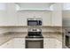 Close-up of a modern kitchen featuring white cabinets, granite countertops, and stainless steel appliances at 24065 Canterwood Way, Venice, FL 34293