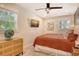 Bright bedroom features a comfortable bed, artwork, ceiling fan, and natural light from multiple windows at 2908 Gulf Dr, Holmes Beach, FL 34217