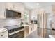 Updated kitchen with stainless steel appliances, white cabinets, modern backsplash, and eat-in island at 2908 Gulf Dr, Holmes Beach, FL 34217