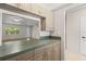 Kitchen pass through with neutral cabinets and green countertop to living room with wood floors and large window at 3212 Ramblewood N Dr # 3212, Sarasota, FL 34237