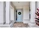 Close-up of front door with wreath flanked by white pillars, colorful plants and brick-paved walkway at 3707 Wild Blossom Pl, Parrish, FL 34219
