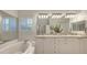 Bright bathroom featuring double sinks, granite countertops, white cabinetry, and a soaking tub at 4208 Balmoral Way, Sarasota, FL 34238