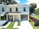Front exterior view of a raised two-story duplex with light yellow paint and wide driveway at 4209 W Woodlawn Ave, Tampa, FL 33614