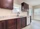 Stylish kitchen with dark cabinets, granite countertops, stainless steel dishwasher, and a view to the backyard at 4209 W Woodlawn Ave, Tampa, FL 33614