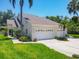 Charming home featuring a three-car garage, well-maintained lawn, and lush tropical landscaping at 6222 Country Club Way, Sarasota, FL 34243