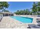 Inviting community pool with brick paver deck, screened in gazebo, surrounded by lush tropical landscaping, and comfortable lounge chairs at 6222 Country Club Way, Sarasota, FL 34243