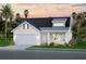 Charming single-Gathering home featuring a light-colored exterior, dormer window, and attached two-car garage at 651 Maldives Trl, Sarasota, FL 34234