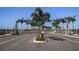 Community entrance featuring a decorative gate, landscaped median, and palm trees along the roadway at 655 Maldives Trl, Sarasota, FL 34234