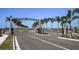 Community entrance with a decorative gate, lush landscaping, and palm tree-lined street at 655 Maldives Trl, Sarasota, FL 34234