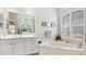 Bright bathroom with a soaking tub, large mirror, dual sinks, white cabinets, and plantation shutters at 7126 Southgate Ct, Sarasota, FL 34243