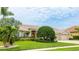 Exterior view of a well-maintained home featuring lush landscaping, a green lawn, and a three-car garage at 7126 Southgate Ct, Sarasota, FL 34243