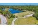 Aerial view of a golf course with a water hazard, surrounded by lush green trees and fairways at 7160 Cedar Hollow Cir, Bradenton, FL 34203
