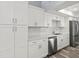 Well-lit kitchen featuring white cabinets, a stainless steel dishwasher, and updated flooring at 800 S Blvd Of The Presidents # 5, Sarasota, FL 34236