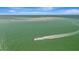 Scenic aerial shot of boat speeding across clear water, island in the distance at 880 N Shore Dr, Anna Maria, FL 34216