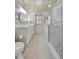 A well-lit bathroom featuring white cabinets, a framed mirror, shower with pebble floor and terrazzo floors at 880 N Shore Dr, Anna Maria, FL 34216