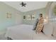 A bright bedroom features a white bedspread, tropical throw pillows and a decorative ceiling fan at 880 N Shore Dr, Anna Maria, FL 34216