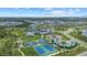 Panoramic aerial view showcasing community amenities like tennis courts, pool and playground amidst lush green spaces at 10120 Canaveral Cir, Sarasota, FL 34241
