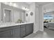 Modern bathroom featuring a double sink vanity, white countertop, gray tile, and bedroom view at 10120 Canaveral Cir, Sarasota, FL 34241