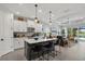 Open-concept kitchen with white cabinetry, island with seating, and views of the living area and outdoor pool at 10120 Canaveral Cir, Sarasota, FL 34241