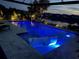 Beautifully lit pool with in-pool seating overlooking a tranquil lake at twilight in the background at 10120 Canaveral Cir, Sarasota, FL 34241