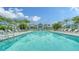Stunning community pool with lounge chairs and covered cabanas surrounded by palm trees on a sunny day at 10186 Crystal Isle Cir, Sarasota, FL 34241