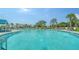 Beautiful community pool featuring zero entry, palm trees, lounge chairs, and nearby covered seating area at 10186 Crystal Isle Cir, Sarasota, FL 34241